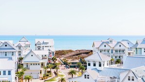 A coastal residential area with white buildings, a wooden pier, and a view of the ocean. - Let's "glow" Girls 113 Tai-d (Port Aransas)