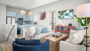 A spacious living area with a sofa, coffee table, and a kitchen in the background. - Let's "glow" Girls 113 Tai-d (Port Aransas)
