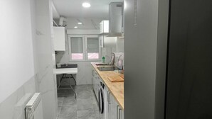 Una cocina compacta con refrigerador, pileta y una encimera de madera.