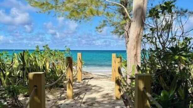 Ein sandiger Pfad führt zu einem Strand mit freiem Blick auf das Meer.