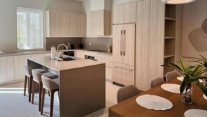 Eine moderne Küche mit Kochinsel, eingebauten Schränken und einer Essecke mit Holztisch und Stühlen.
