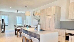 A modern kitchen with a central island, bar stools, and a dining area with a table and chairs. - New luxury 1bd - Gated - Pool,  Beach and Gym access - Quiet and Relaxing (Nassau)