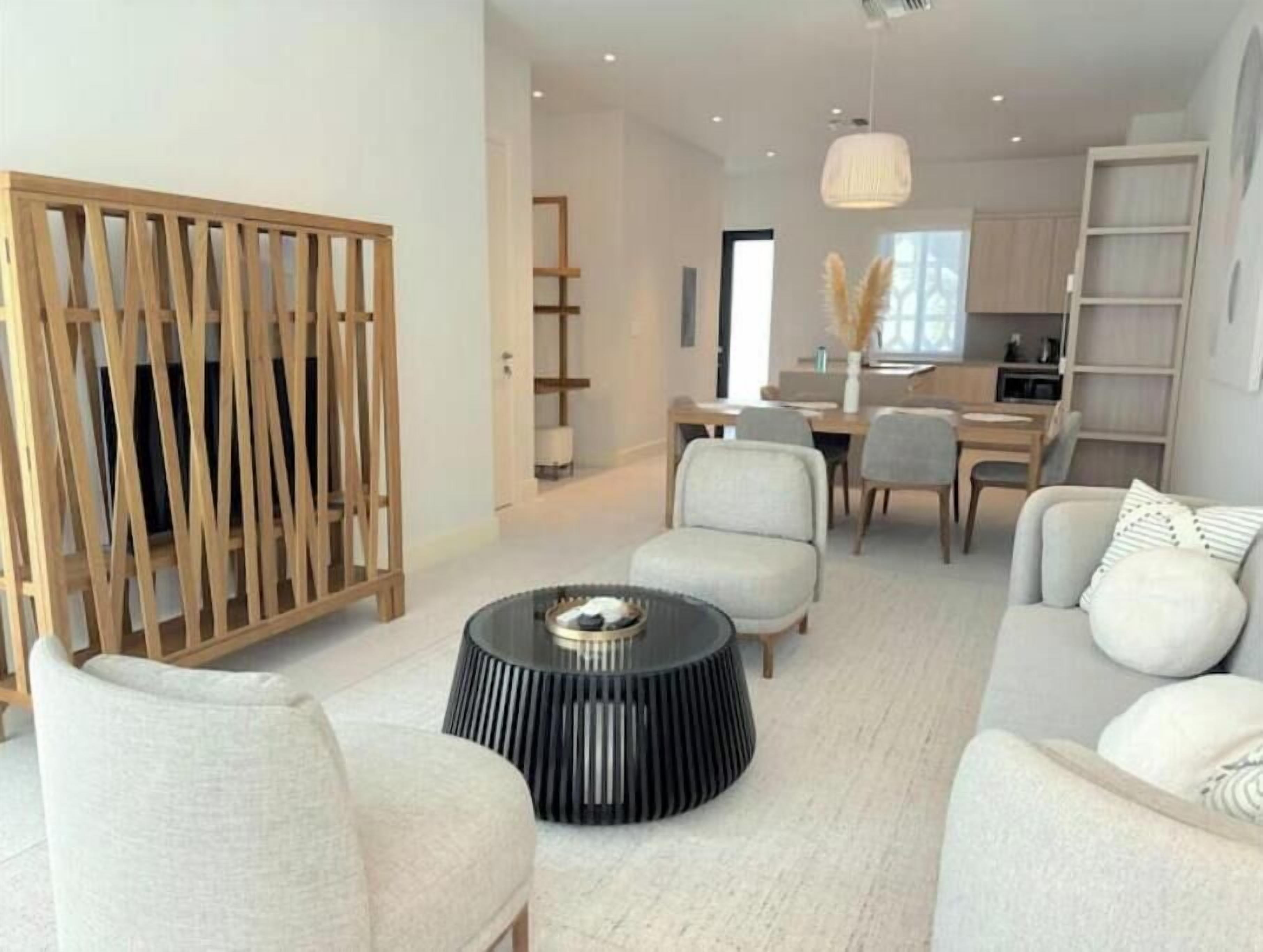 A modern living room with a sofa, armchairs, a coffee table, and a wooden partition.
