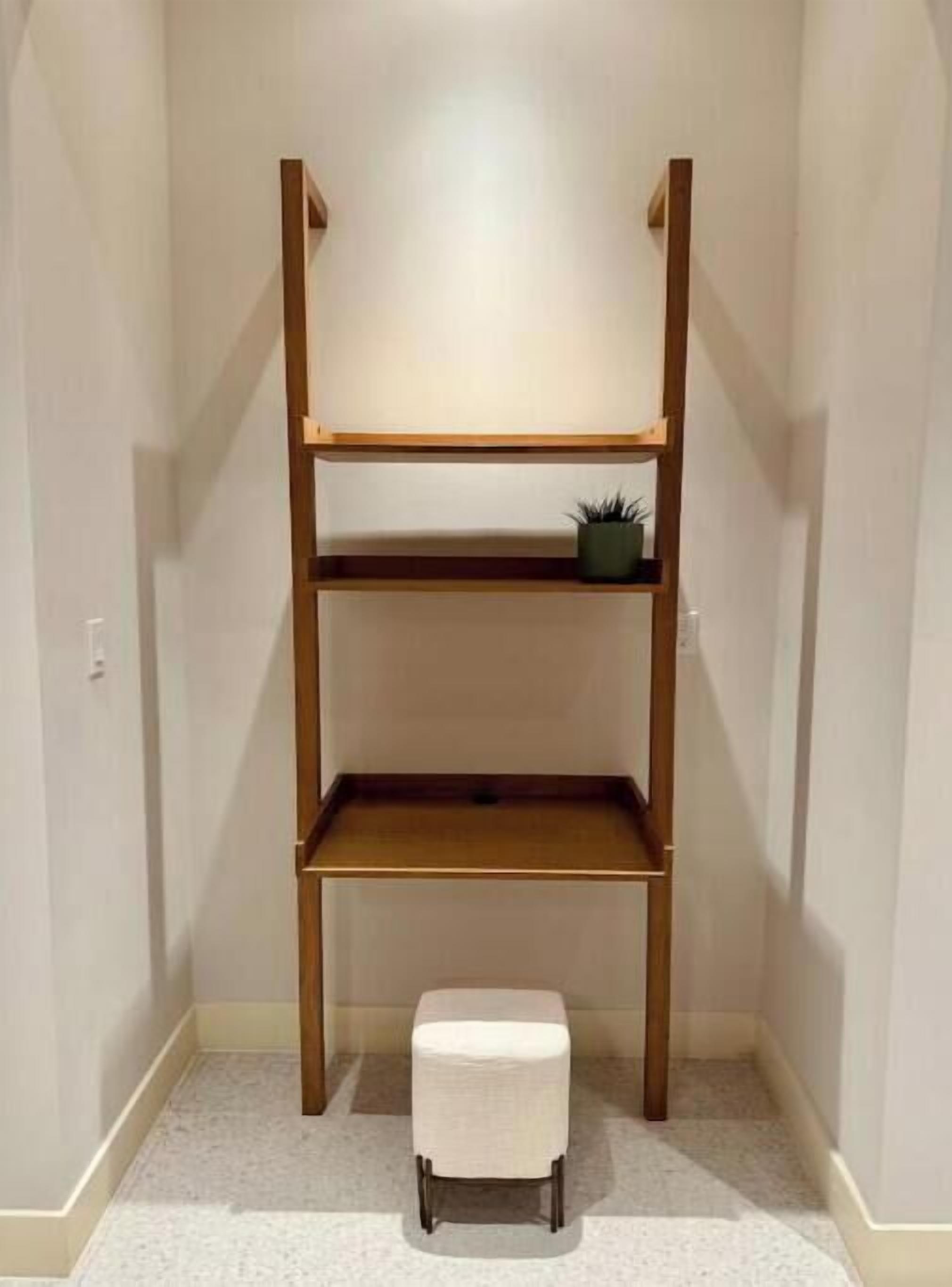 Een hoekkamer met een houten wandplank, een klein krukje en een potplant.