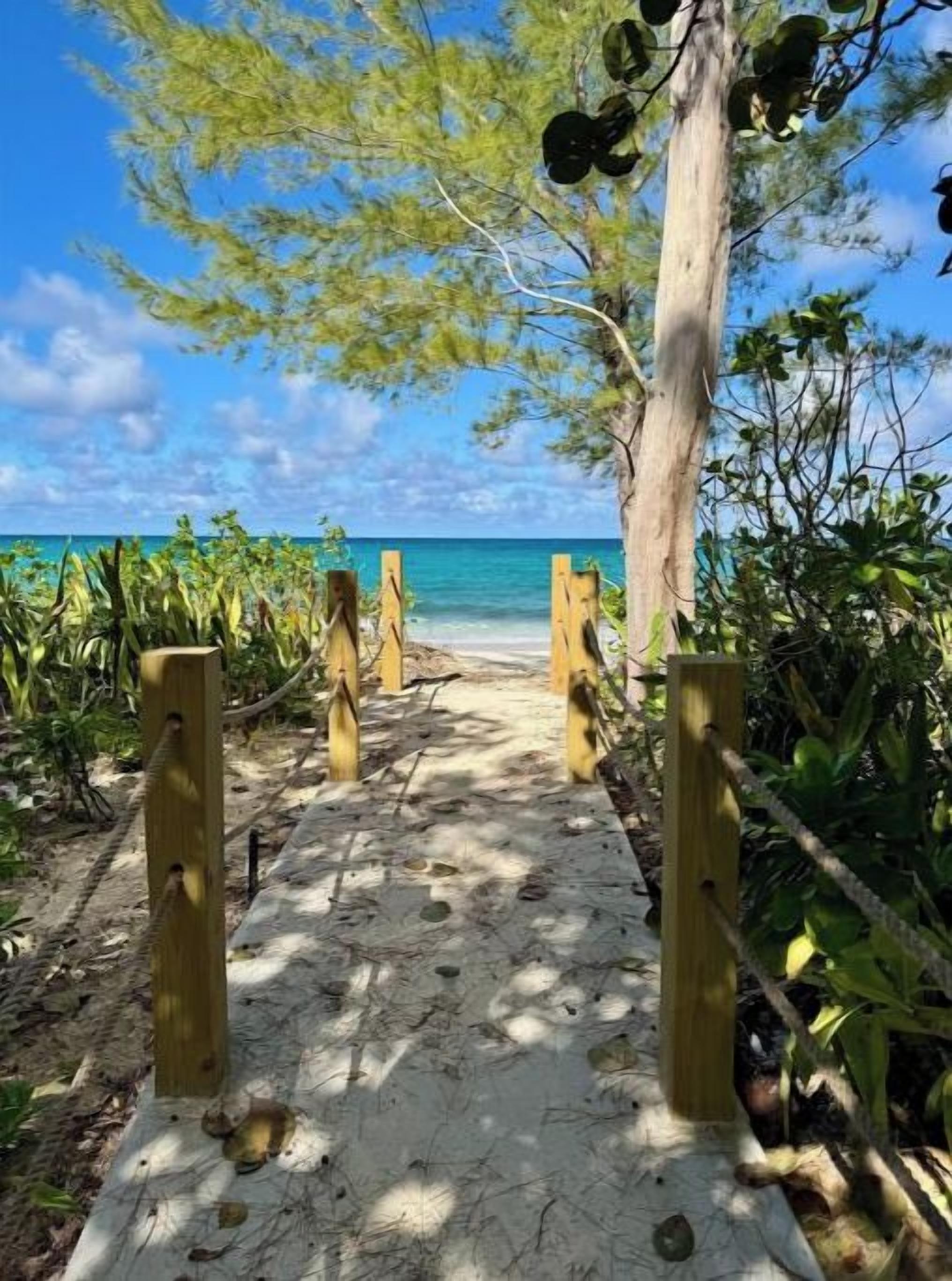 A sandy pathway leading to a beach with a clear view of the ocean.
