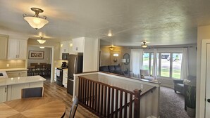A spacious kitchen with a central island, wooden flooring, and a view to the living area.