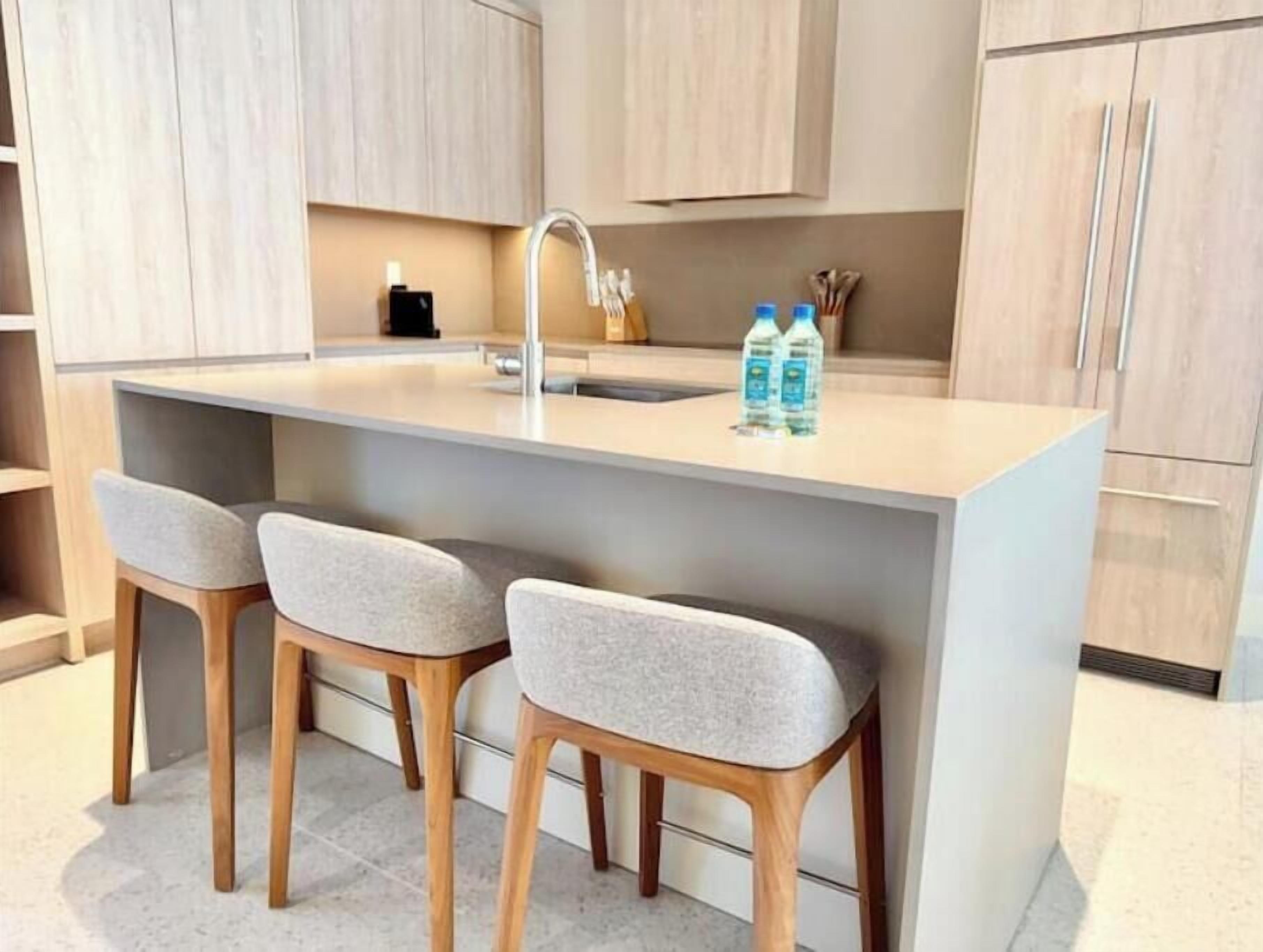 Cozinha moderna com ilha central, dois bancos e uma pia.