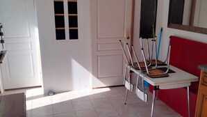 A room with a white door, a window with blinds, a red wall, a table with a chair, and a ceiling light fixture. - House with Tree-filled Garden (Saumur)