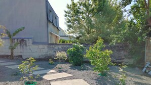 A garden pathway leading to a building with a stone wall and greenery. - House with Tree-filled Garden (Saumur)