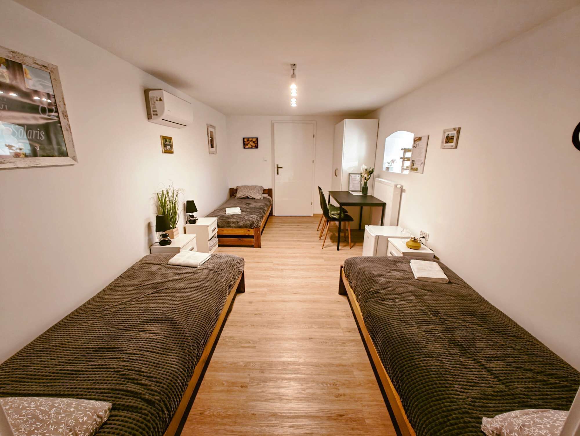 A small, well-lit room with two single beds, a desk, a chair, and a radiator.