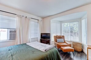 Ein Hotelzimmer mit einem Bett, einem Fernseher, einem Ledersessel und einem Fenster mit Jalousien.