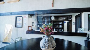A reception desk with a vase of flowers, a clock, and a cross on the wall. - Hotel Villalba (Comitán de Dominguez)
