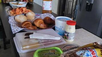 Una encimera de cocina con diversos alimentos y condimentos, como pan, queso y una botella de jugo.