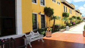 A yellow building with a white bench and potted plants in a courtyard. - Hotel Villalba (Comitán de Dominguez)