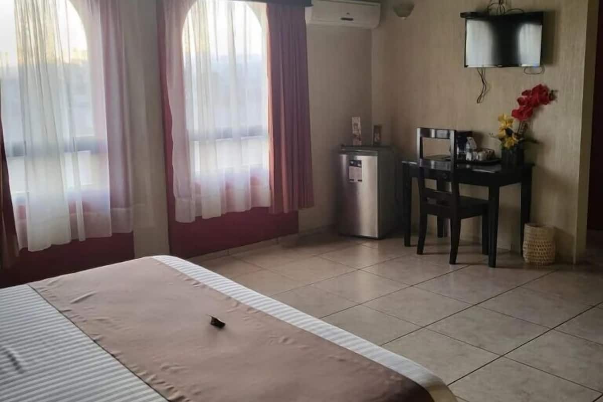 Une chambre d’hôtel avec un lit, un bureau, une chaise et un téléviseur.