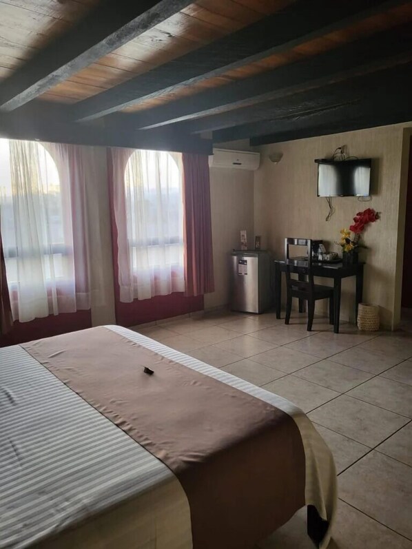 Una habitación de hotel con cama, escritorio, silla y televisión.