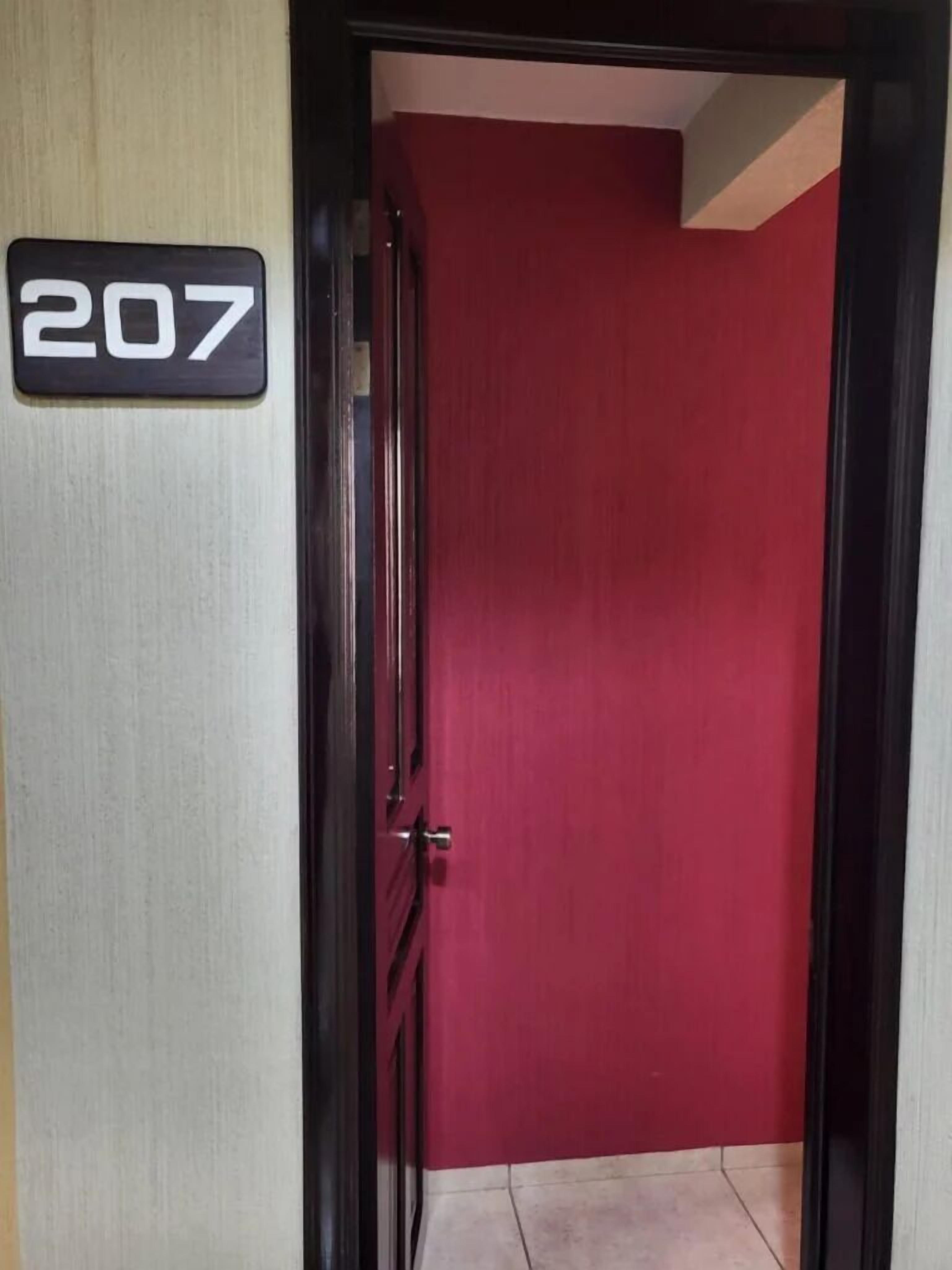 Una puerta con una placa con el número 207 y un marco rojo.
