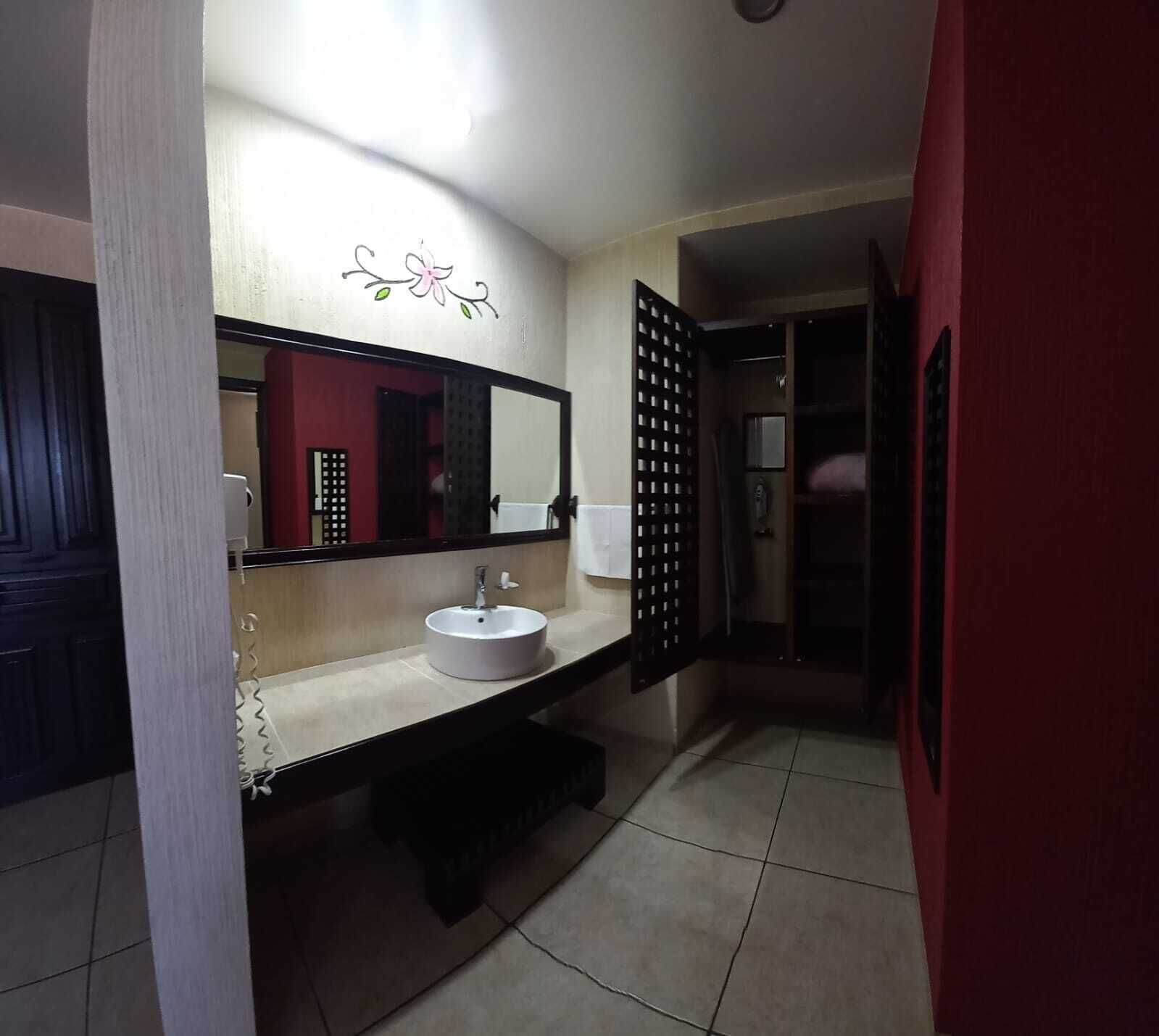 A bathroom with a white sink, a mirror, and a red door.