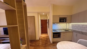 A modern kitchen with a wooden floor, white cabinets, and a microwave. - Rent Up - Monoambiente Zona Congreso (Buenos Aires)