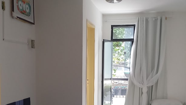 Ein Hotelzimmer mit Bett, Deckenventilator, Fenster mit Vorhängen und Blick ins Freie.