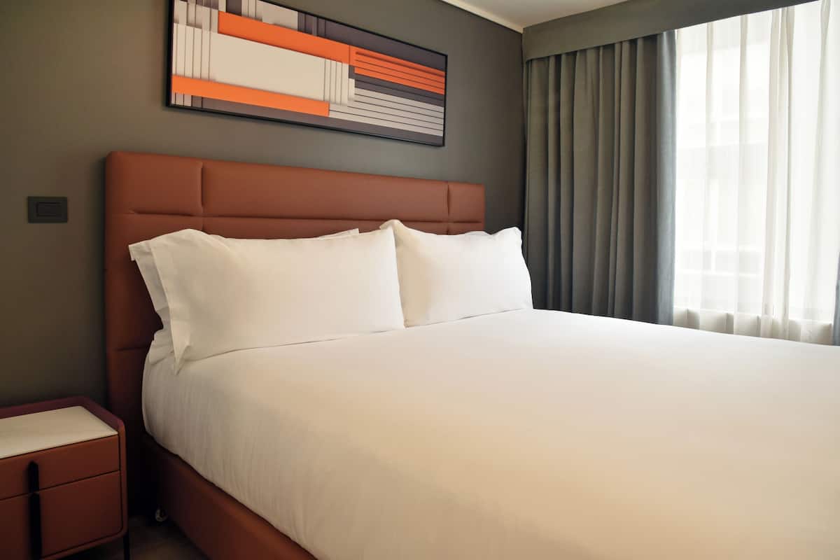 A neatly made bed with white linens in a hotel room.