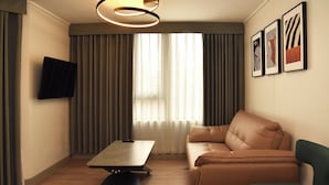 A modern living room with a sofa, a coffee table, and a TV mounted on the wall. - APART HOTEL HW COMPAÑIA (Santiago)