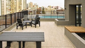 A balcony with a pool view, outdoor seating, and a cityscape in the background. - APART HOTEL HW COMPAÑIA (Santiago)