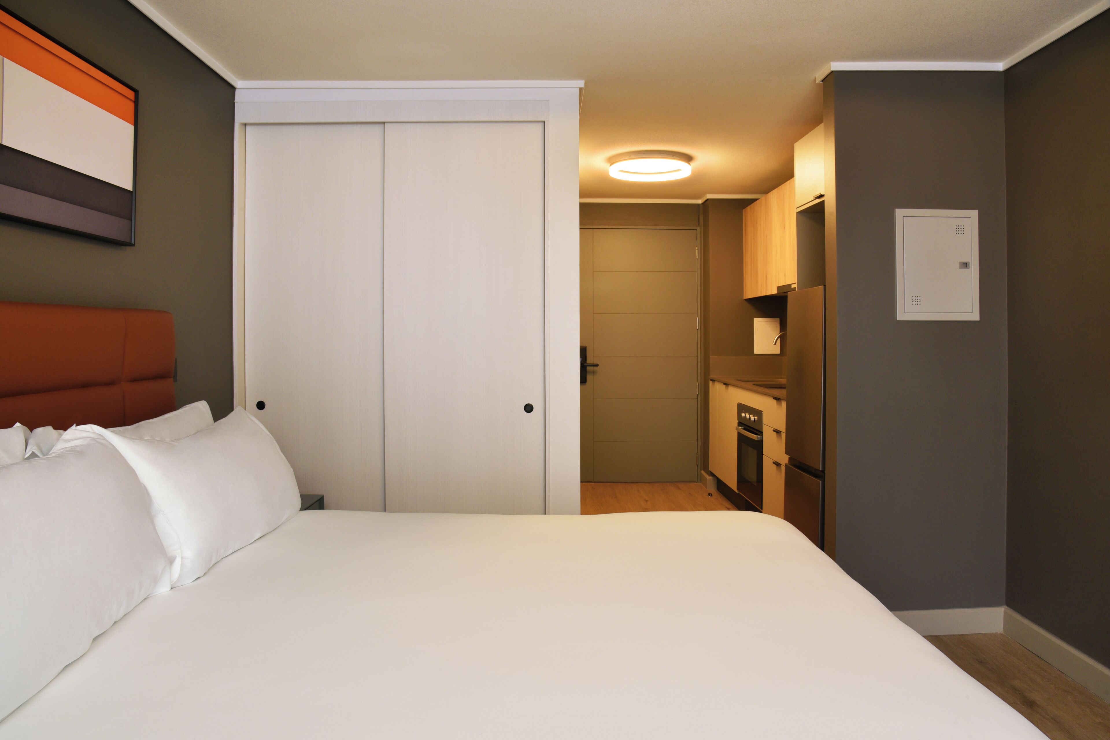 A bedroom with a bed, a wardrobe, and a kitchenette.