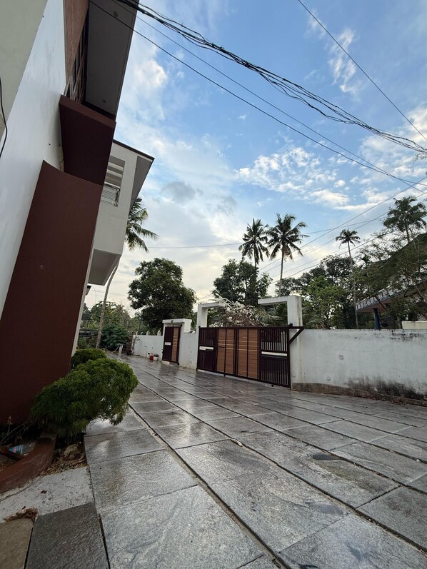A residential street with a gated entrance, a modern building, and palm trees.