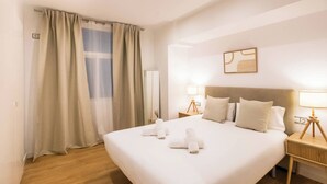 A hotel room with a large bed, two bedside tables with lamps, a mirror, and a window with curtains.