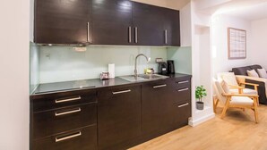 A compact kitchen with dark cabinets, a stainless steel sink, and a coffee machine.