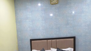 Un dormitorio con cama, ventilador de techo, reloj y mesita de noche.