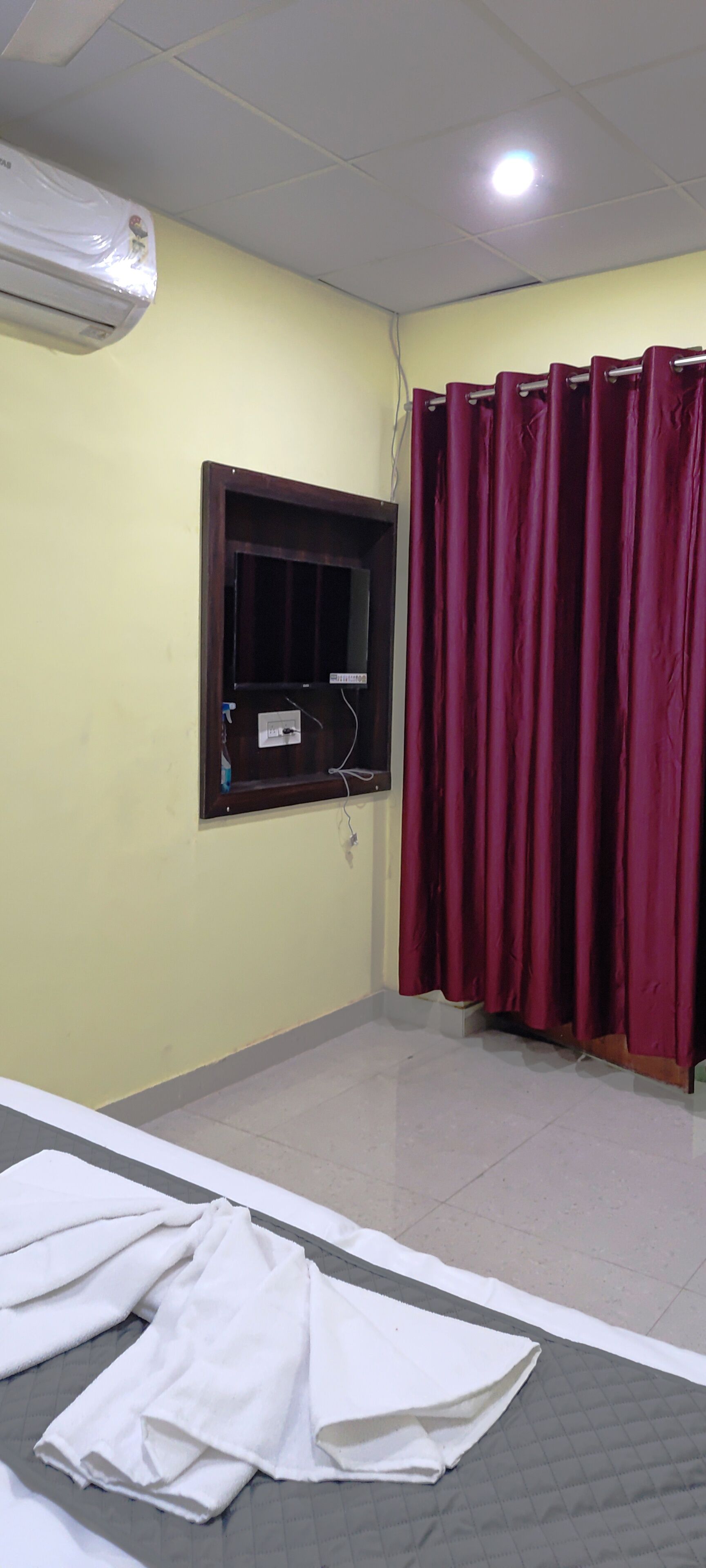 Una habitación con ventana, cortina y cama con sábanas blancas.