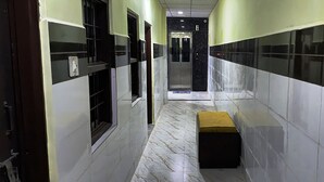 Un pasillo estrecho con suelo de mármol, un banco y una puerta al final.