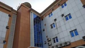 A multi-story building with a mix of glass and tiled facades, air conditioning units, and a satellite dish on the roof. - Milton Park Resorts (Kano)
