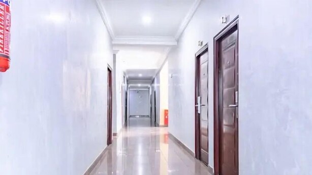 A clean, well-lit hallway with a polished floor, doors on the right, and a fire extinguisher on the left. - Milton Park Resorts (Kano)
