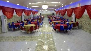 A banquet hall with rows of tables and chairs, air conditioning units, and red drapes. - Milton Park Resorts (Kano)