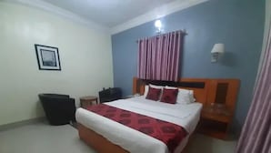 A bedroom with a bed, a nightstand, a wall-mounted lamp, and a picture frame. - Milton Park Resorts (Kano)