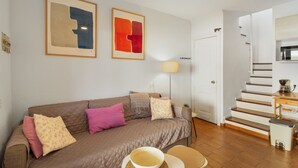 Una sala de estar con un sofá marrón, una mesa de centro y una escalera que sube a un piso superior.
