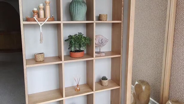 A wooden shelving unit with various decorative items including plants, candles, and a woven basket. - Apartment in Cartagena (Cartagena de Indias)