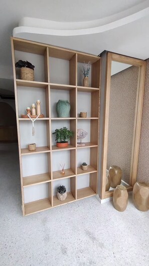 A wooden shelving unit with various decorative items including plants, candles, and a woven basket. - Apartment in Cartagena (Cartagena de Indias)