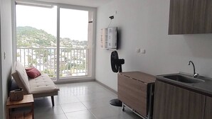 A modern kitchen with a built-in oven, a sink, and a wooden cabinet. There is a sliding glass door leading to a balcony with a city view. - Apartment in Cartagena (Cartagena de Indias)