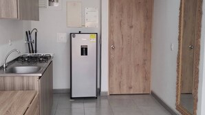 A modern kitchen with a built-in gas stove, a stainless steel refrigerator, and wooden cabinets. - Apartment in Cartagena (Cartagena de Indias)