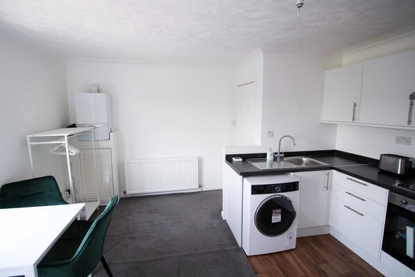 A compact kitchen with a washing machine, a sink, and a toaster.