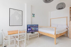 Un dormitorio con una cama de madera, un escritorio con una silla, un televisor y un cuadro en la pared.