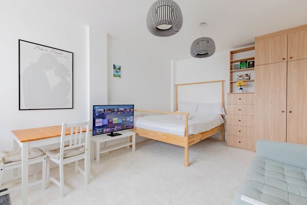 A bedroom with a bed, a desk, a TV, and a wardrobe.