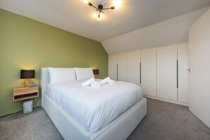 Ein Schlafzimmer mit Bett, Nachttischen, Deckenleuchte und Einbauschränken.