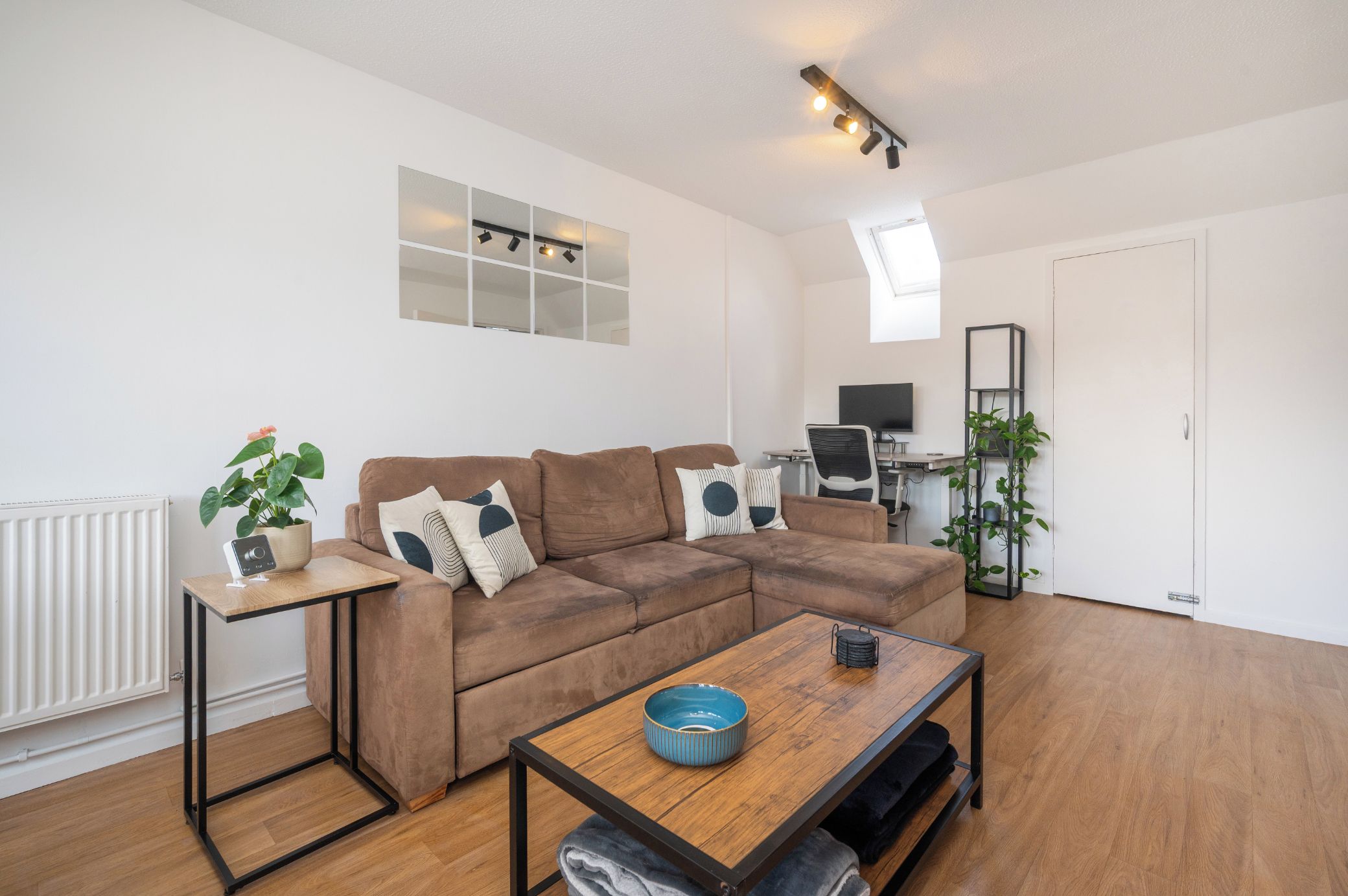 A modern living room with a brown sectional sofa, a wooden coffee table, and a TV on a desk.