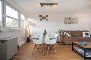 A modern living room with a dining table, white chairs, a sofa, and a coffee table.