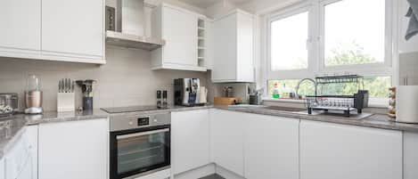 A modern kitchen with white cabinetry, a built-in oven, and a window providing natural light.